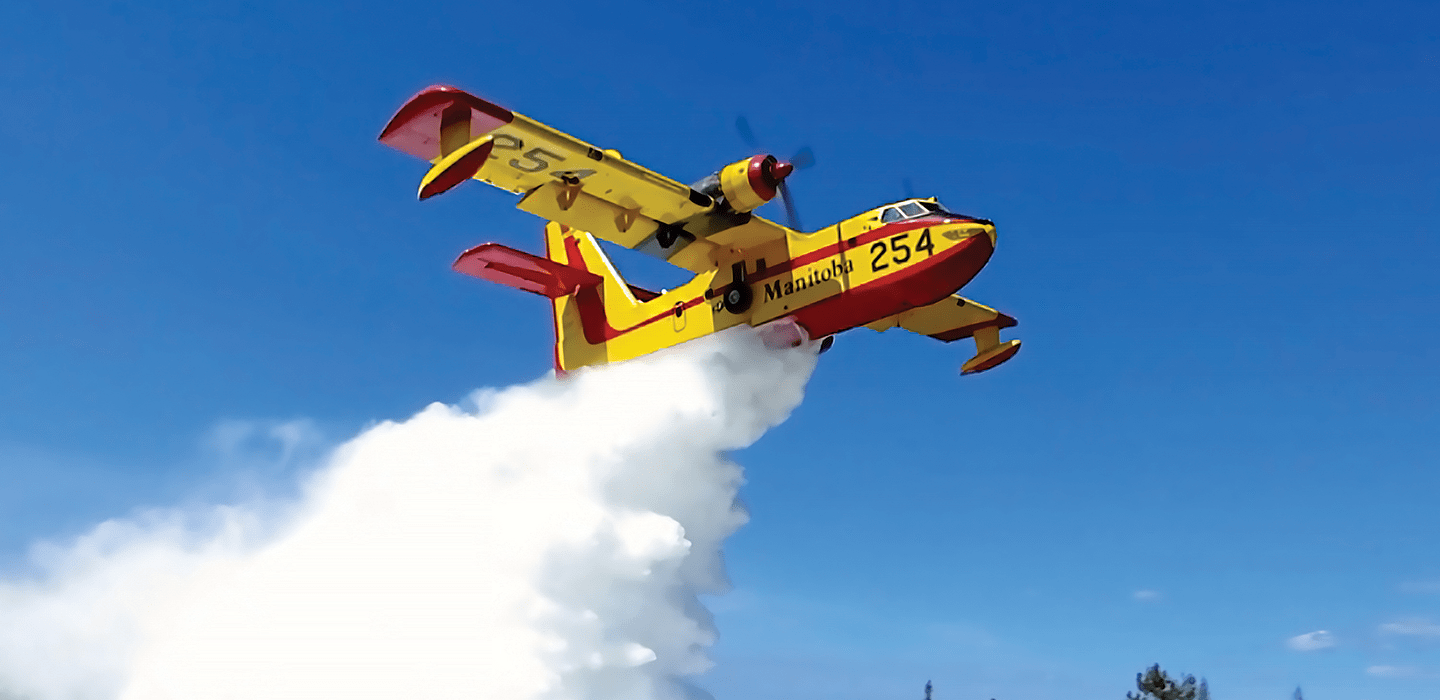 Babcock CL-415 water bomber dropping water over a Manitoba forest
